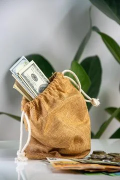 A brown cloth bag with a drawstring sits on a white surface. The bag is fil.. Stock Photos
