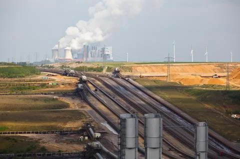 A brown coal surface mine with conveyor belts leading to a distant coal power Stock Photos