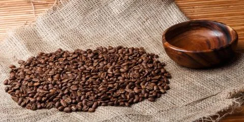 Brown coffee beans on the bag with empty wooden dish and bamboo background Stock Photos
