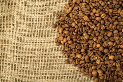 Brown coffee beans on burlap Stock Photos