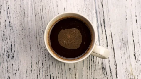 Brown coffee with bubbles in white cup. Liquid rotating in cup. Top down close Stock-Footage 121568074