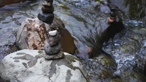 A brown colored hand stacking another small rocks to the stacked rocks Stock Footage 204886105