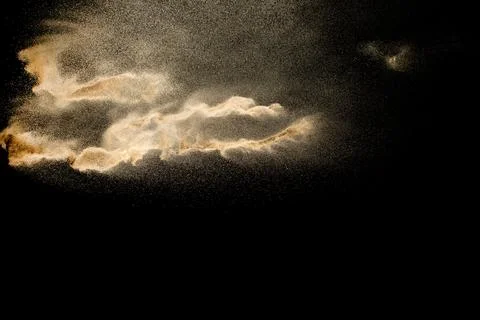 Brown colored sand splash against dark background. Dry river sand explosion.. Stock Photos