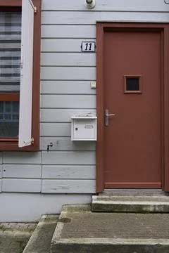 The brown door featuring a mailbox is located on a charming gray wooden hou.. Stock Photos