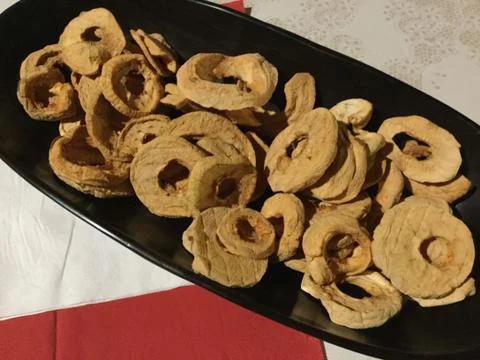 Brown dried apple rings in a black bowl on a table 库存照片