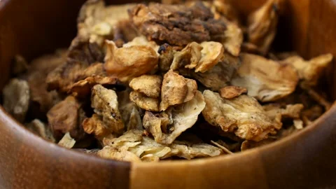 Brown dried chicory root slices falling down into the wooden bowl close up Stock-Footage 311799031