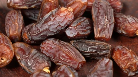 Brown dried date fruits falling down slowly on bottom of bowl background Video stock 155873633