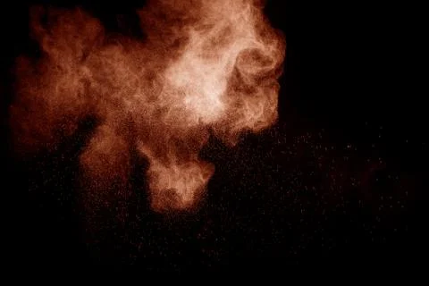 Brown dust explosion cloud.Brown particles splatter on black background. Stock Photos