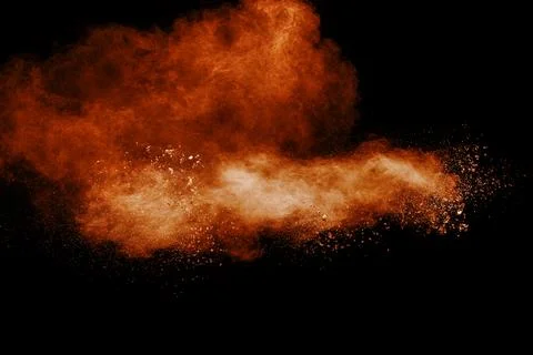 Brown dust explosion cloud.Brown particles splatter on black background. Stock Photos