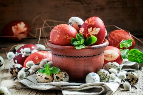 Brown easter egg with a pattern with small speckled quail eggs in a clay bowl Stock Photos