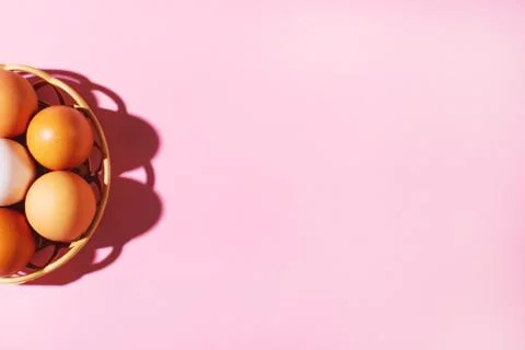 Brown easter eggs in basket on pink background. Stock Photos