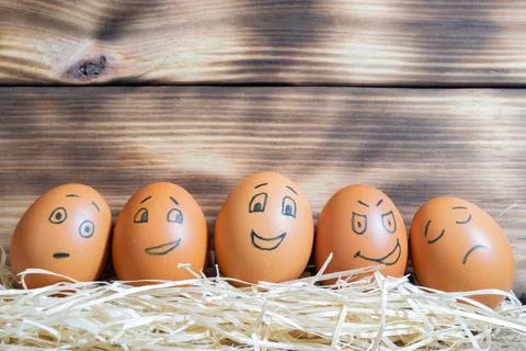 Brown easter eggs with funny faces on a wooden background Stock Photos