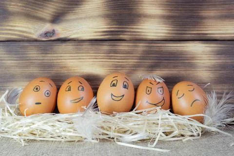 Brown easter eggs with funny faces on a wooden background Stock Photos