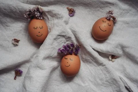 Brown Easter eggs with a painted face with a flower wreath on the linen cloth Stock Photos