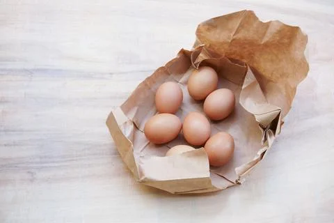 Brown egg in paper bag behind ,Fresh chicken eggs on wood table Foto stock