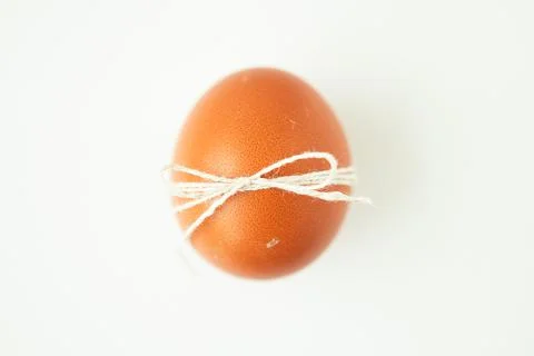 Brown egg wrapped with thread on white background with copy space Stock Photos