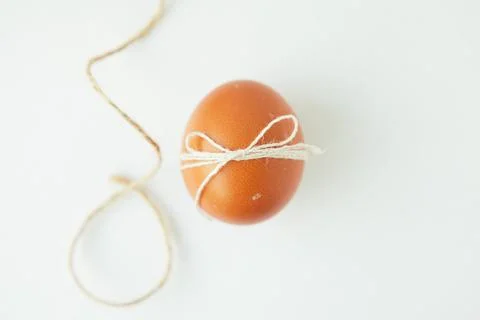 Brown egg wrapped with thread on white background Stock Photos