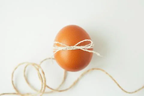 Brown egg wrapped with thread on white background Stock Photos