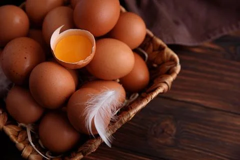 Brown eggs in basket with broken egg yolk Stock Photos