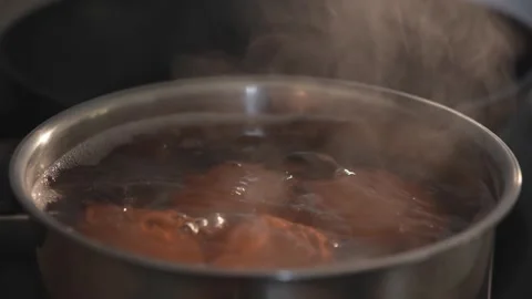 Brown eggs boiling in steaming pot on kitchen stove Stock Footage 312767181