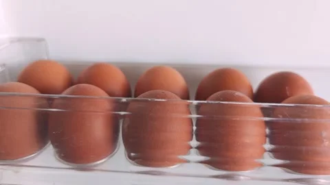 Brown eggs gradually shift in a clear plastic carton, showcasing a continuous Stock Footage 334324342