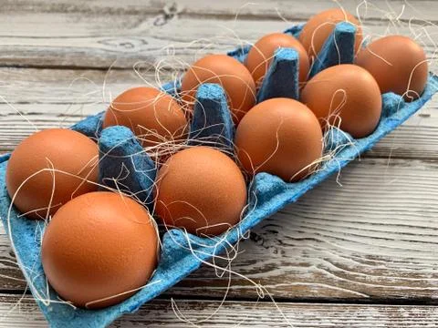 Brown eggs lay in a blue box in the background. Country style. Stock Photos