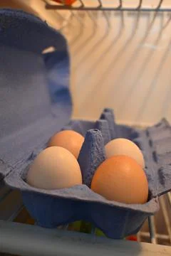 Brown eggs in an open carton inside a refrigerator 库存照片
