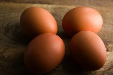 Brown Eggs on Wooden Surface in Dramatic Low-Key Lighting Foto stock
