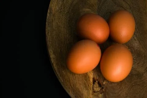Brown Eggs on Wooden Surface in Dramatic Low-Key Lighting Stock Photos