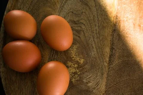 Brown Eggs on Wooden Surface in Dramatic Low-Key Lighting Foto stock