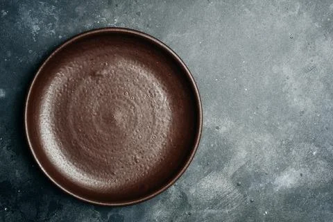 Brown empty plate handmade ceramic on gray stone background. Copy space. Stock Photos