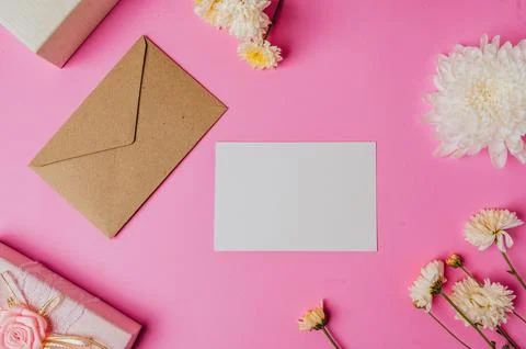 Brown envelope, pink giftbox with blank card and flower on pink background Stock Photos