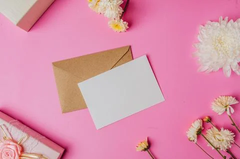 Brown envelope, pink giftbox with blank card and flower on pink background Stock Photos