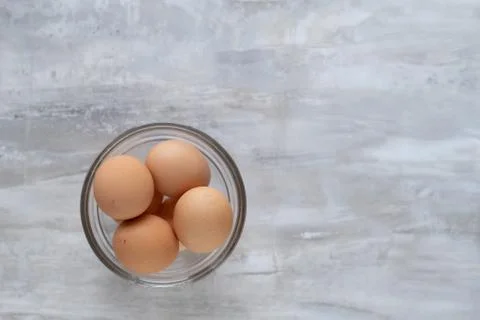 Brown farm eggs in clear bowl on marbled counter Stock Photos