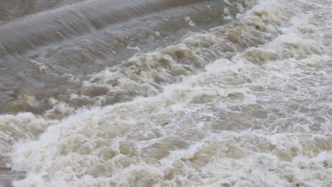 Brown fast-flowing river water flowing over weir Stock Footage 328715965