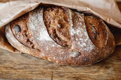Brown fresh bread with seeds on old wood background. Top view, copy space Stock Photos