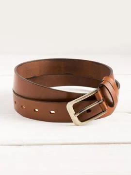 Brown genuine leather belt on a white wooden background. Stock Photos