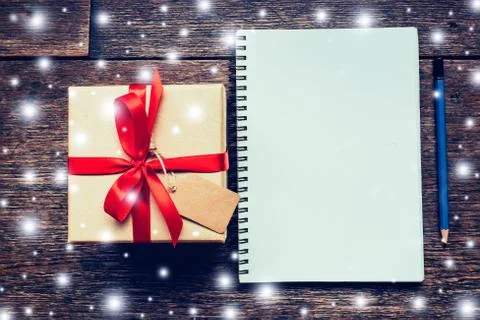 Brown gift box and notebook, pencil with snow white on wood board backgroun.. Stock Photos