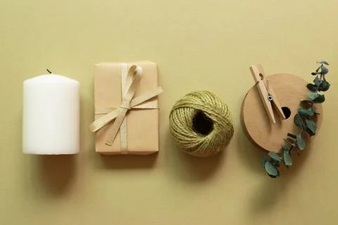 Brown gift box, string reel, candle on khaki green background Stock Photos