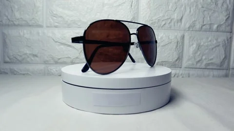 Brown glasses rotating on a white surface, highlighting their stylish desig.. Stock Footage 297148805