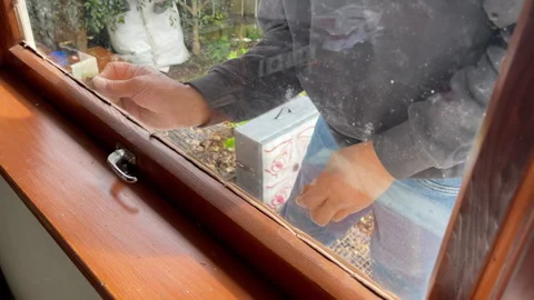Brown glazing putty being used to hold a new window in place Stock Footage 280954392