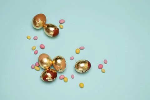 Brown-golden easter pattern eggs and colored sweets in jelly beans on blue Foto stock