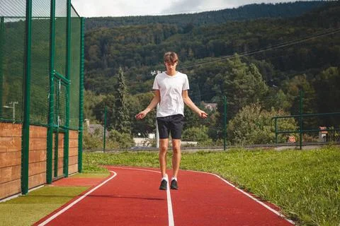 Brown-haired boy with an athletic figure wearing a white T-shirt and black sh Stock Photos