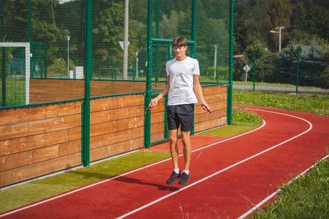 Brown-haired boy with an athletic figure wearing a white T-shirt and black sh Stock Photos