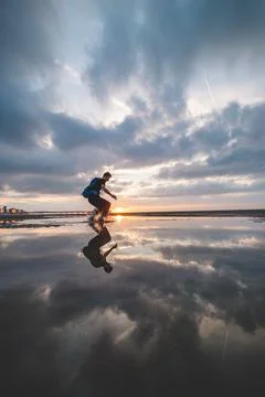Brown-haired man with a backpack, aged 25-29, jumps into a pool of water on t Stock Photos
