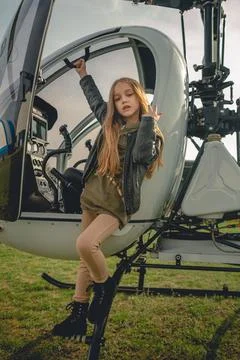 Brown-haired preteen girl standing on footboard of open helicopter Stock Photos
