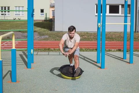 Brown-haired professional athlete does a one-legged squat on a balance beam t Stock Photos