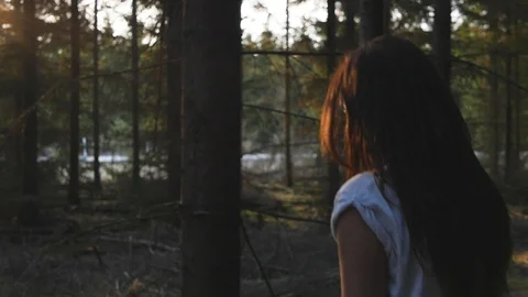 Brown haired tattooed girl walking against the sunlight touching a tree Stock Footage
