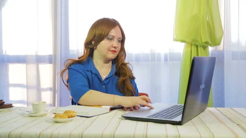 A brown-haired woman in a cafe at a table working with a laptop 库存影片 109558302
