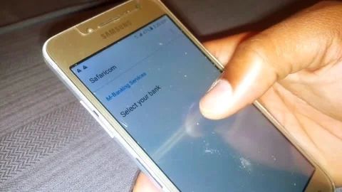 Brown Hand Selecting Safaricom Mobile Banking Service in Kenya Stock Footage 146043022